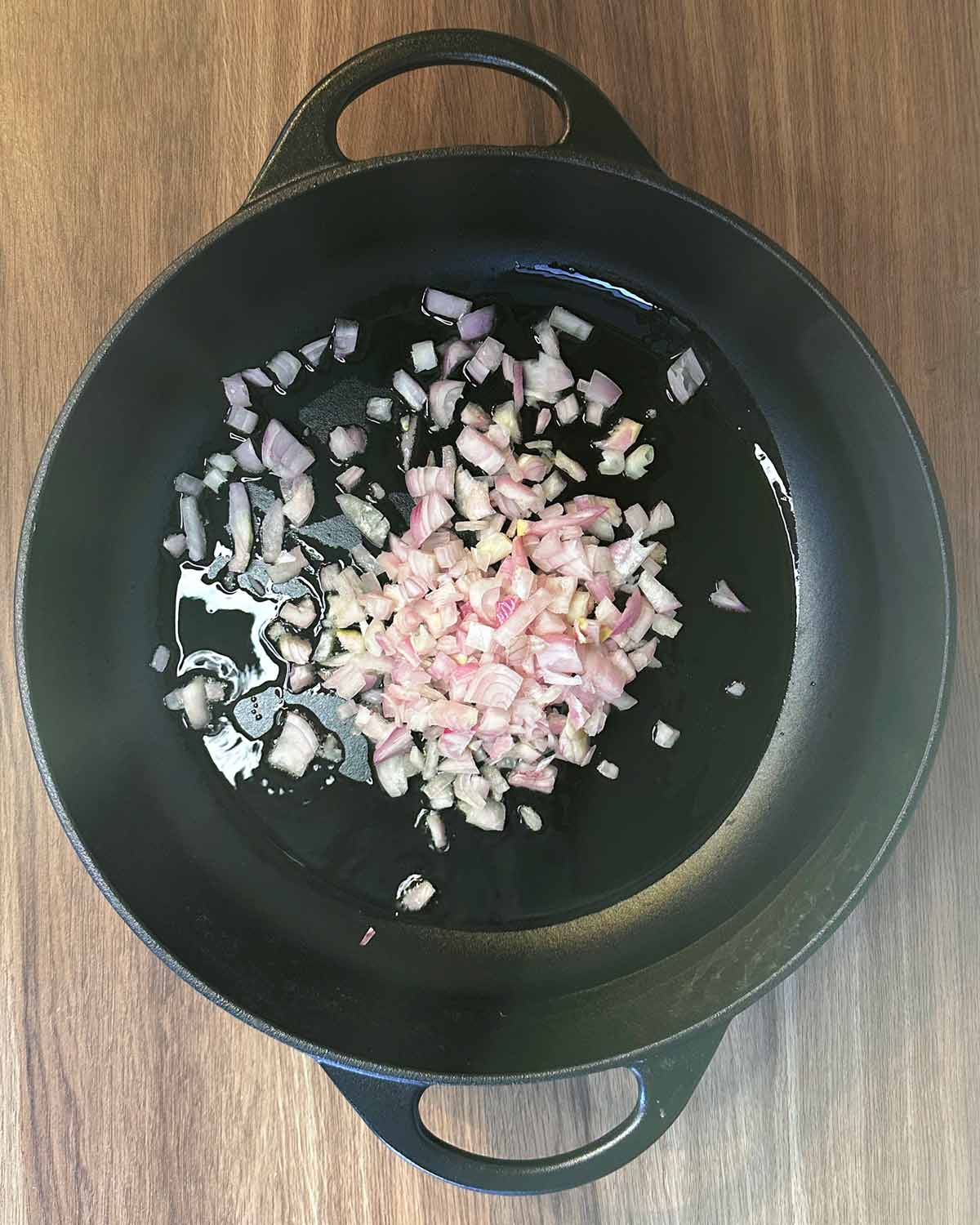 Chopped shallots frying in a pan.
