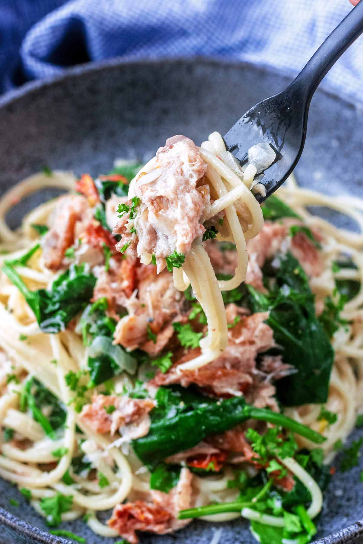 A fork lifting some pasta and flaked mackerel from a bowl.