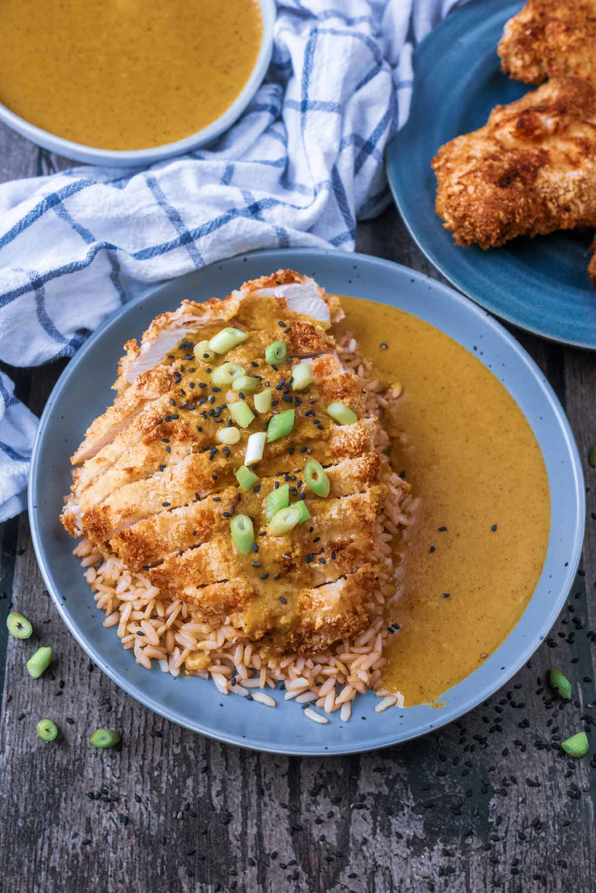 Chicken katsu in a bowl with rice, in front of more chicken.