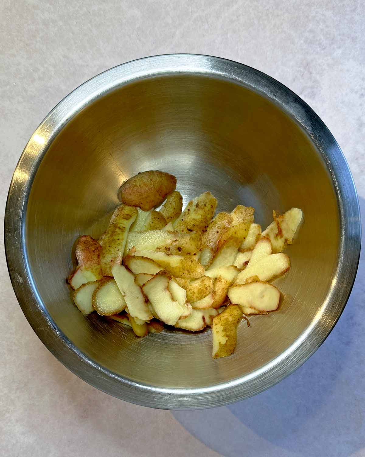 Potato peelings in a bowl with oil and seasoning.