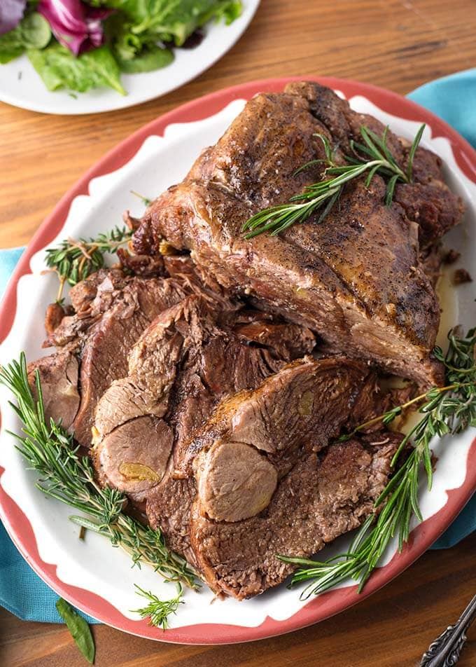Cooked lamb on a plate with sprigs of rosemary.