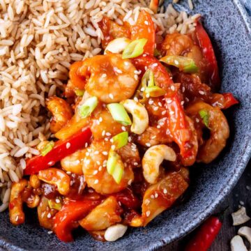 Kung po prawns and brown rice in a grey bowl.