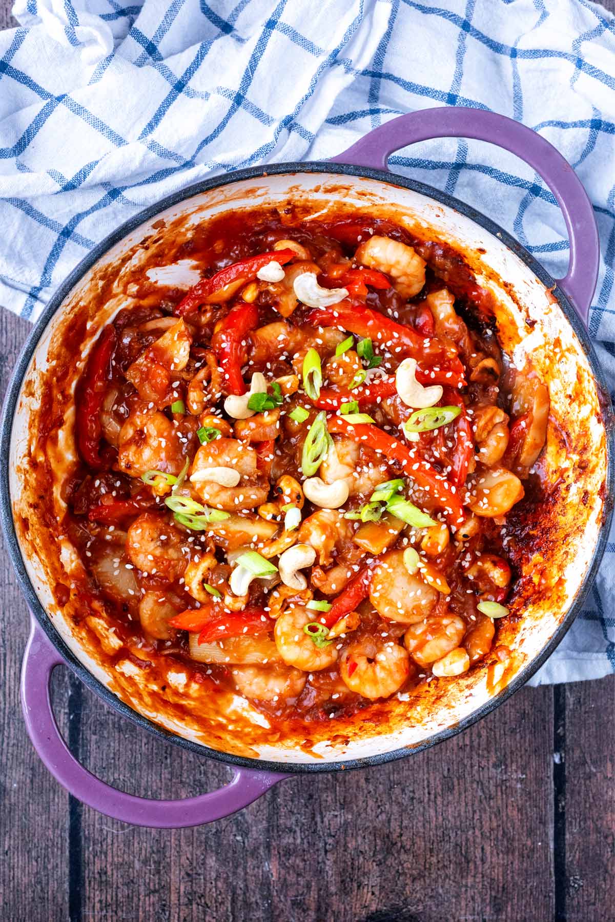 A large pan of cooked prawns and vegetables in a red sauce.