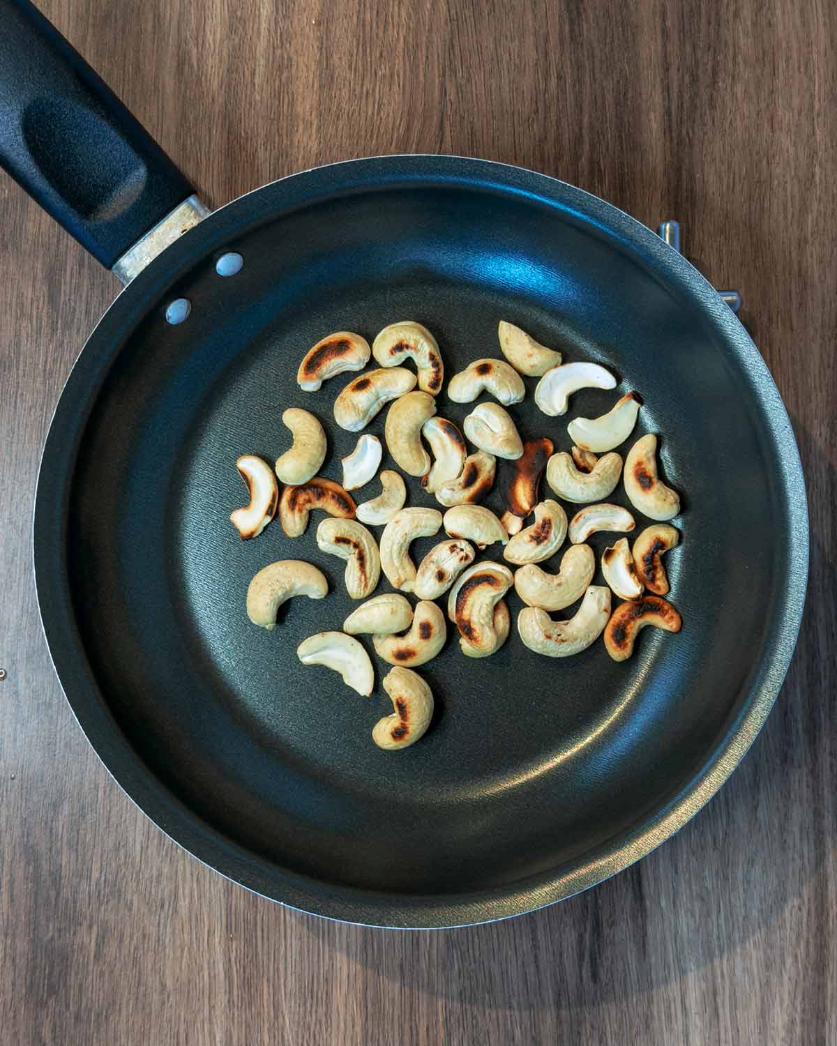 Cashew nuts toasting in a frying pan.