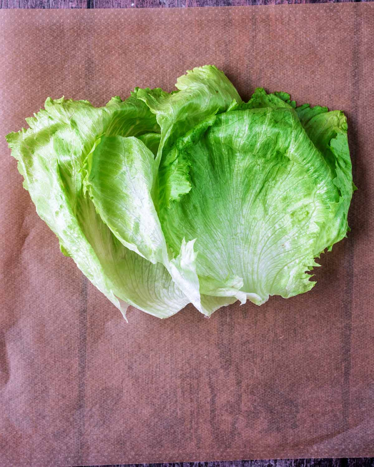 Three iceberg lettuce leaves on some parchment paper.
