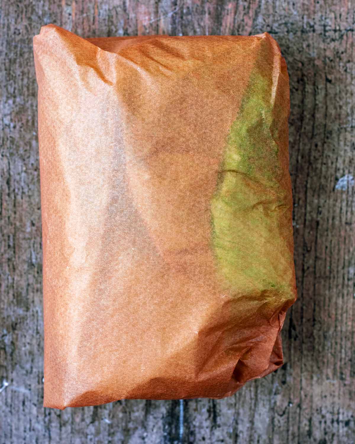 The lettuce wrap folded up and wrapped in parchment paper.