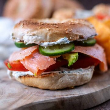 A smoked salmon bagel on a wooden serving board.