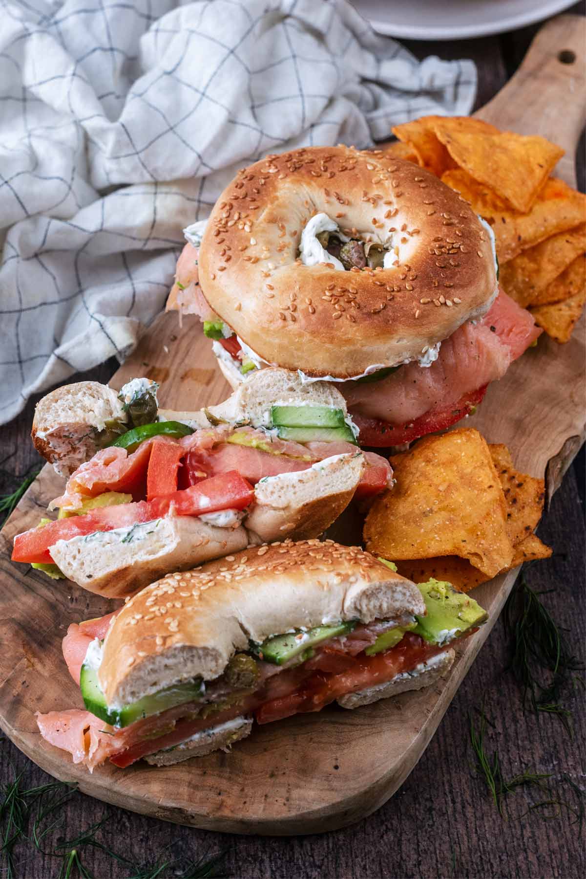 Two filled bagels on a wooden board, one is cut in half.