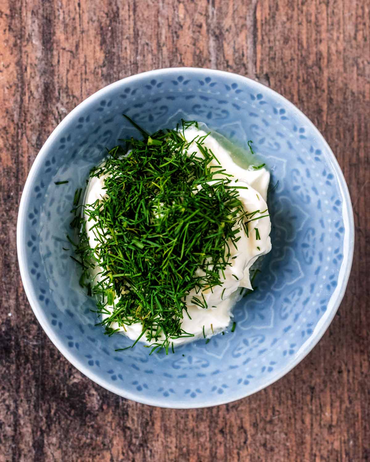 A small bowl with cream cheese and fresh dill in it.
