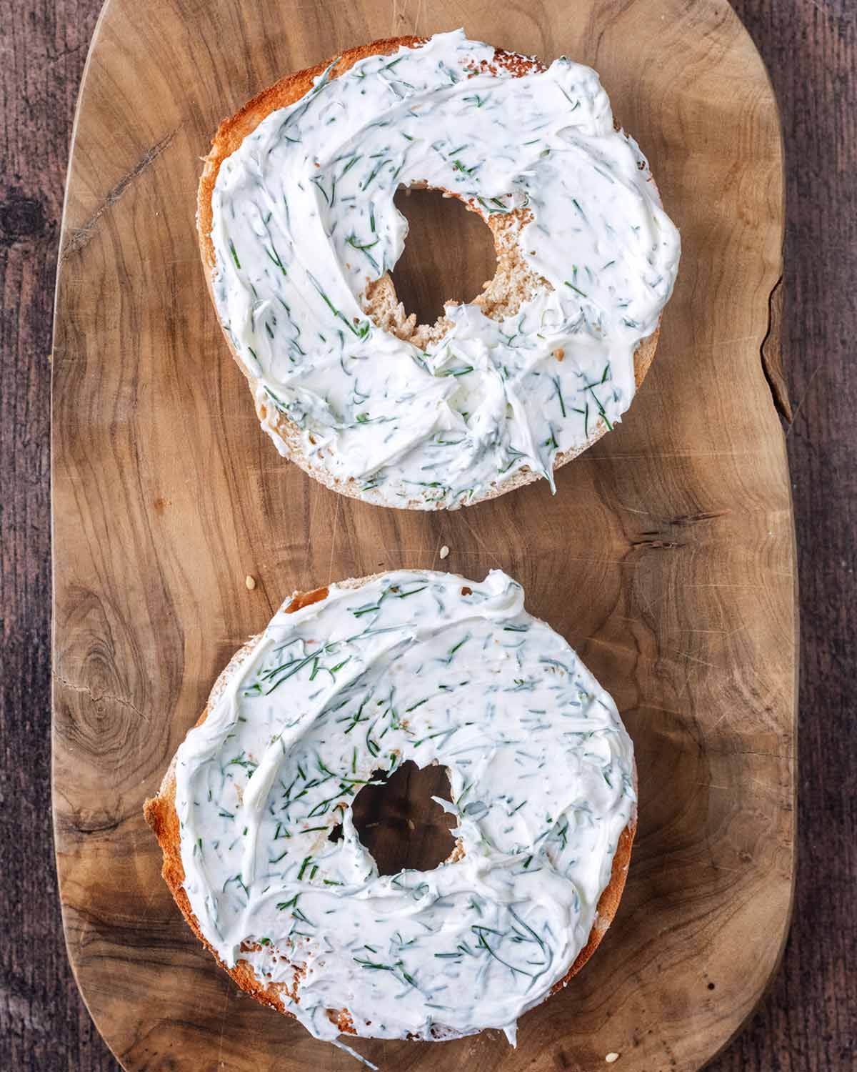 Cream cheese and dill mixture spread over the bagel halved.