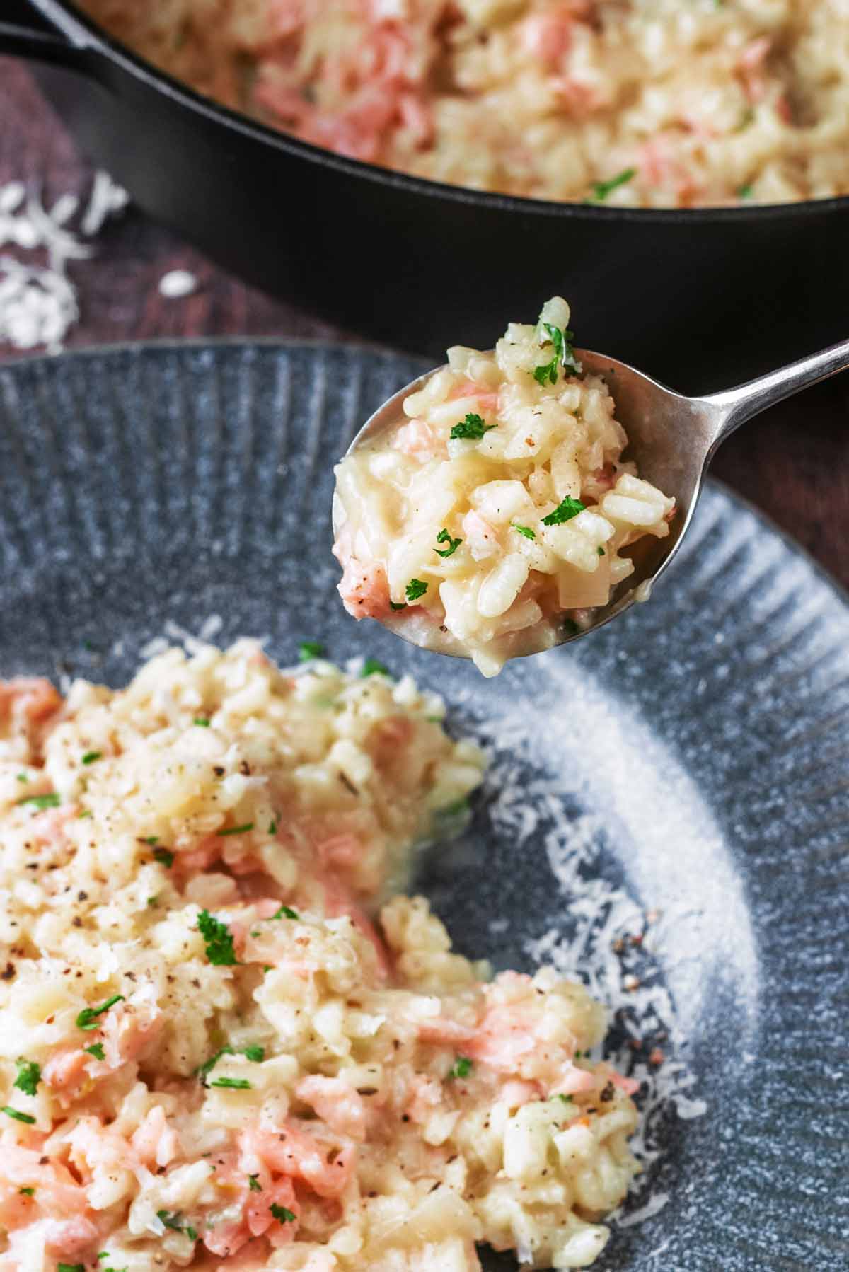 A spoon lifting some risotto from a bowl.
