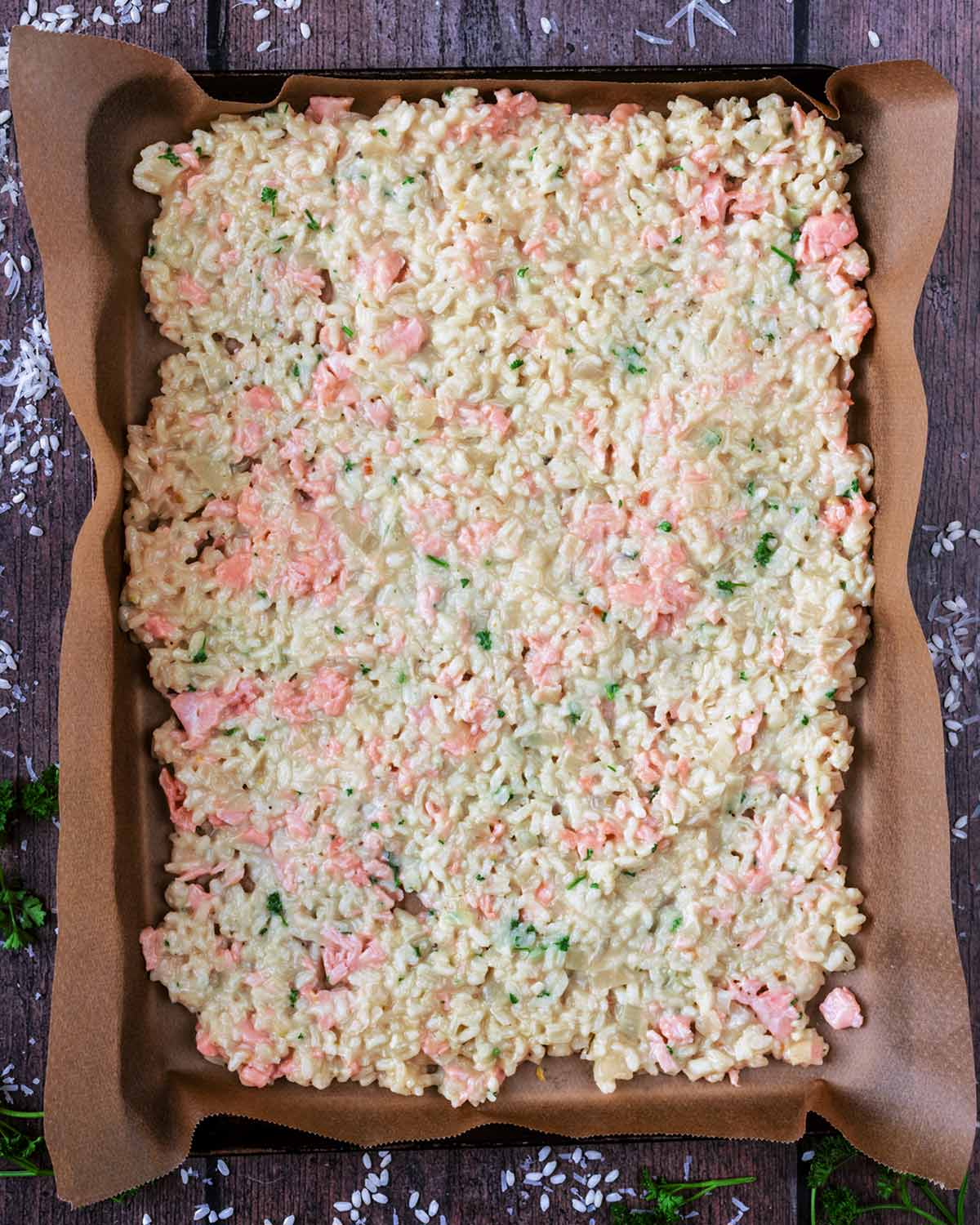Salmon risotto spread out over a large lined baking sheet.
