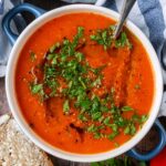 A bowl of air fryer soup topped with a drizzle of oil and chopped herbs.