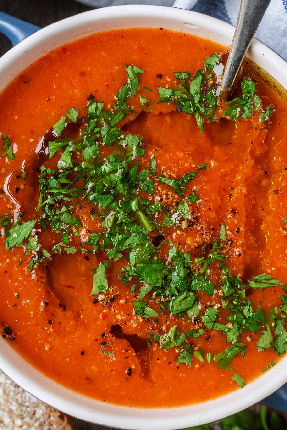 Chopped herbs scattered over tomato soup.