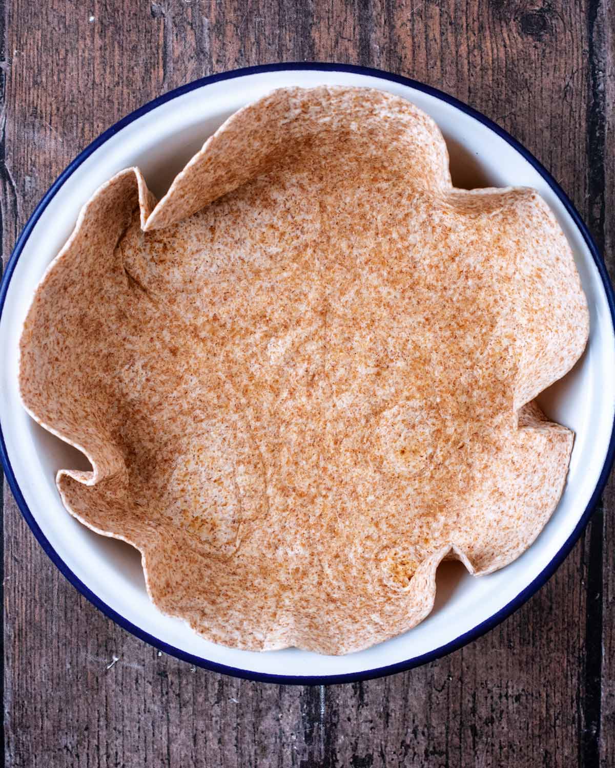 A wholewheat tortilla wrap pressed into a round baking dish.