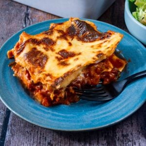 A portion of chicken lasagna on a blue plate.