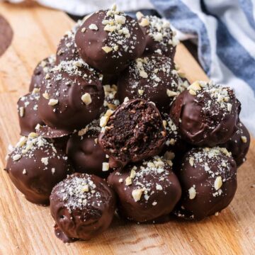 A pile of chocolate covered raw brownie balls on a wooden board.