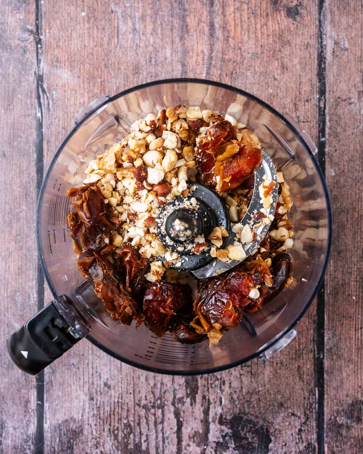 A food processor containing dates and crushed nuts.