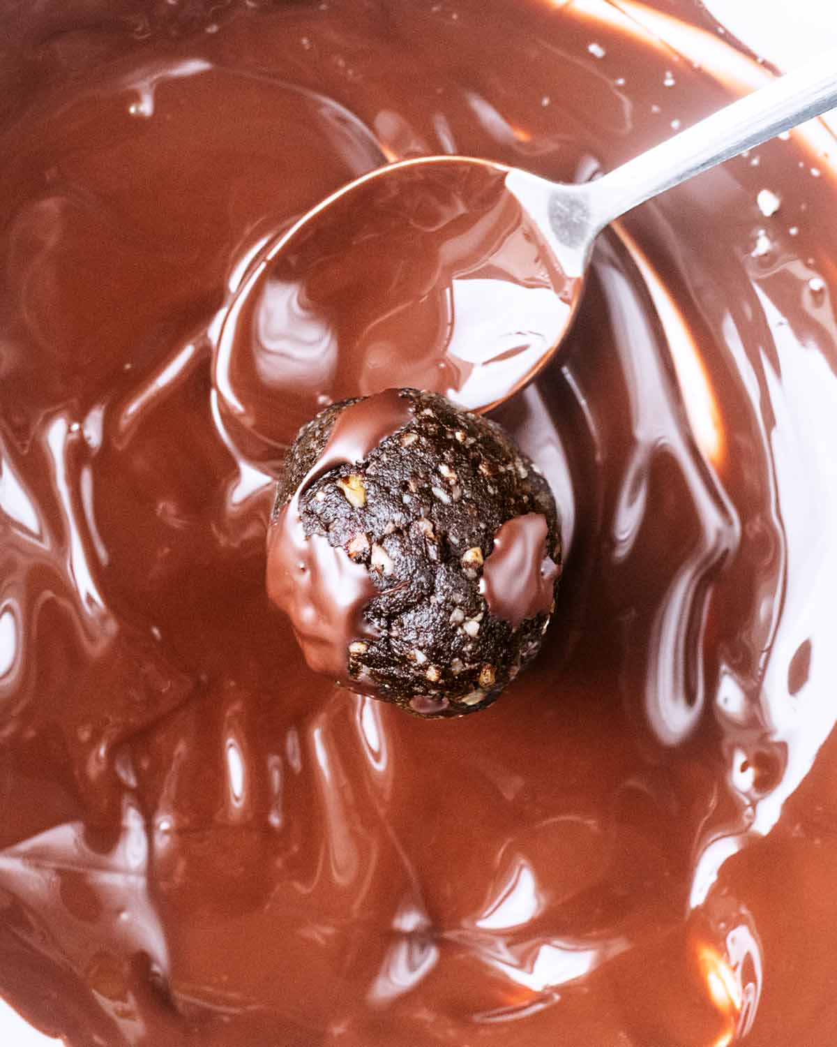 One of the date balls being coated in melted chocolate.