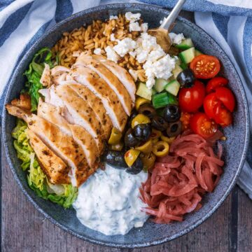 Greek chicken bowl containing chicken, salad, tzatziki and feta.