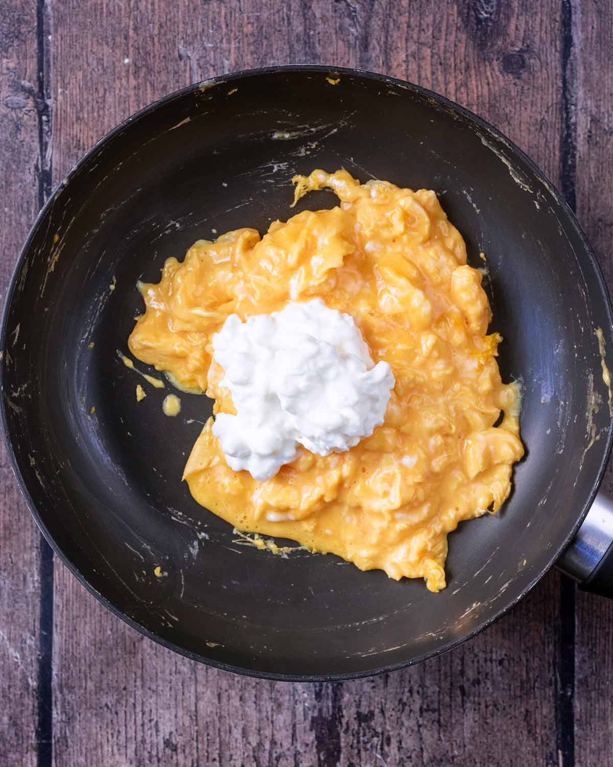 A dollop of cottage cheese on top of the scrambled eggs.