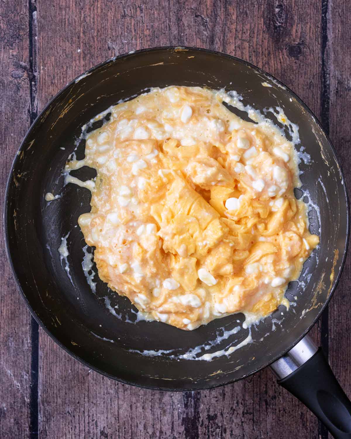 Scrambled eggs and cottage cheese mixed together in the pan.