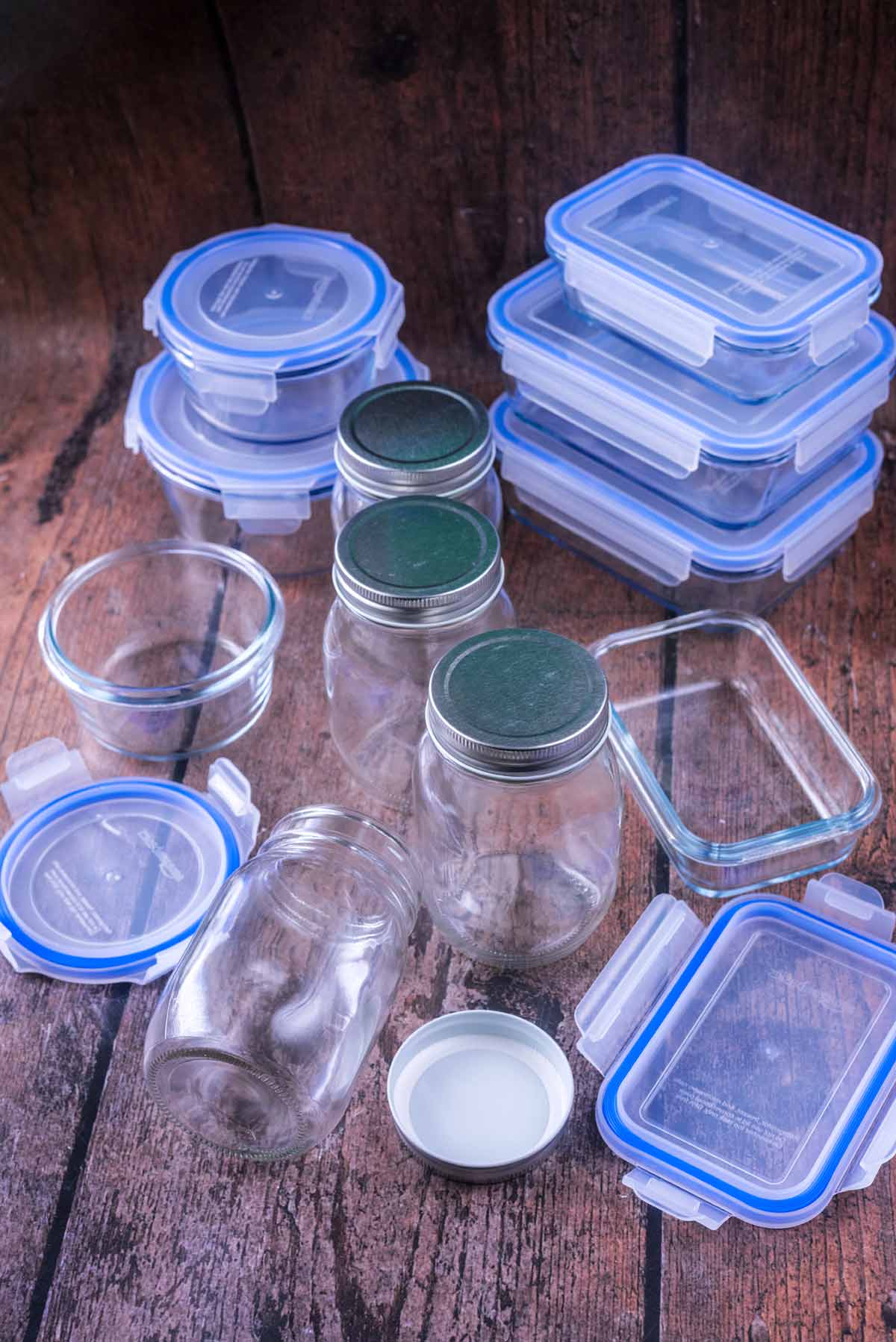 Glass storage containers and glass jars on a wooden surface.