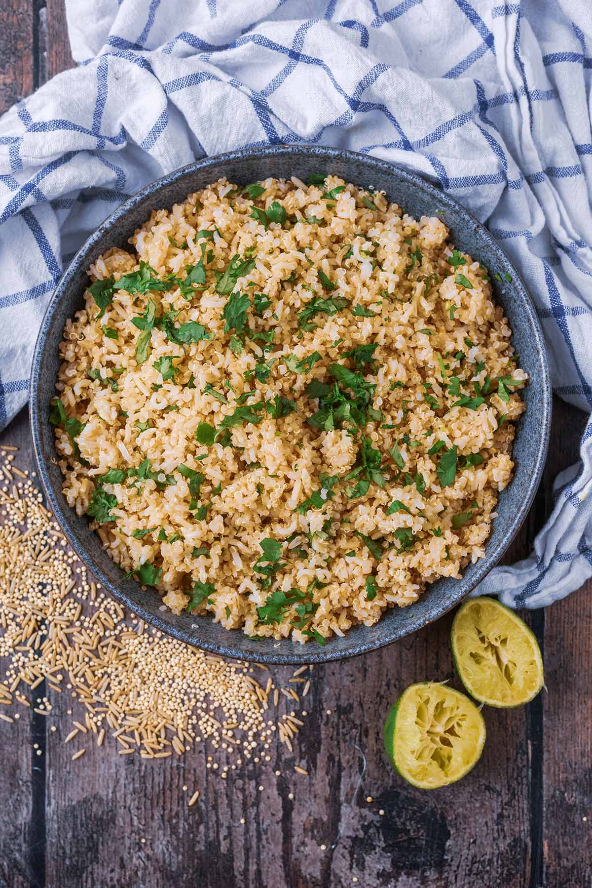 A large bowl of cooked rice and quinoa with chopped herbs scattered on top.