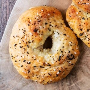 A sesame seed topped cottage cheese bagel on a wooden surface.
