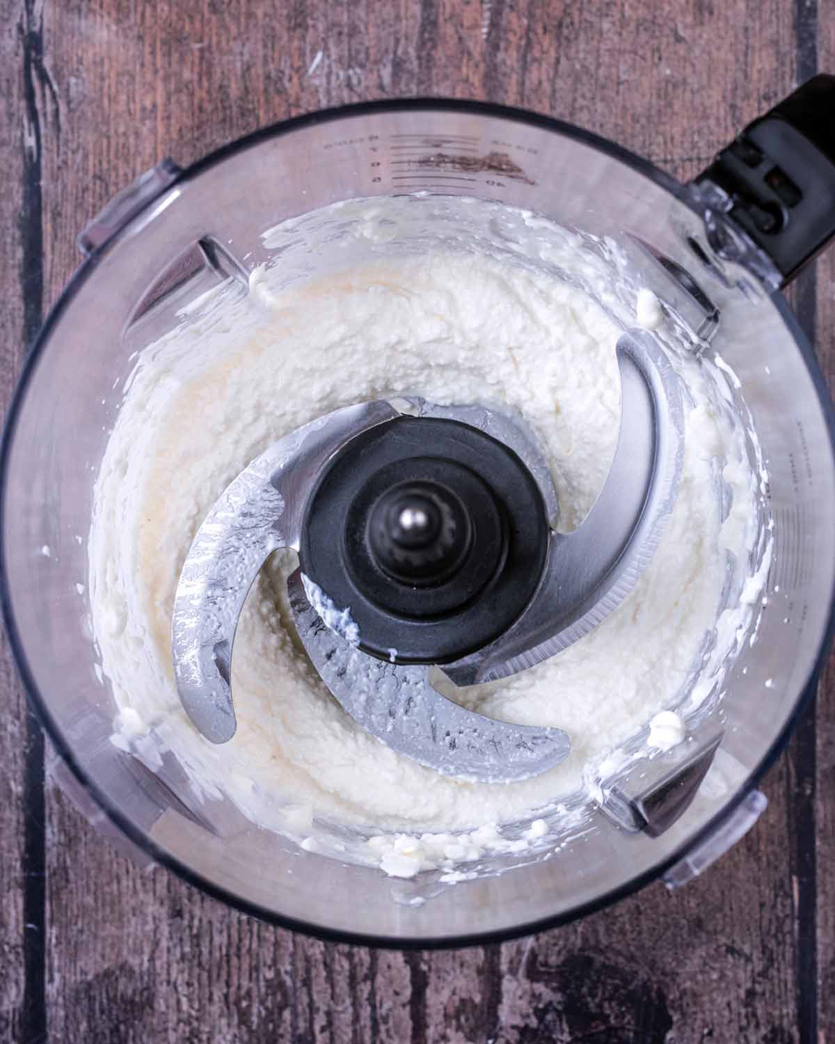 A food processor with blended cottage cheese in it.