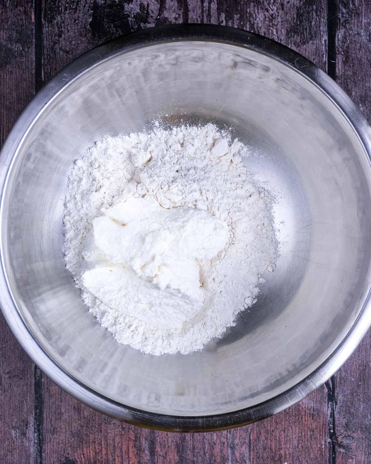 Flour and cottage cheese in a silver mixing bowl.