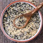 A bowl of everything bagel seasoning with a wooden spoon in it.
