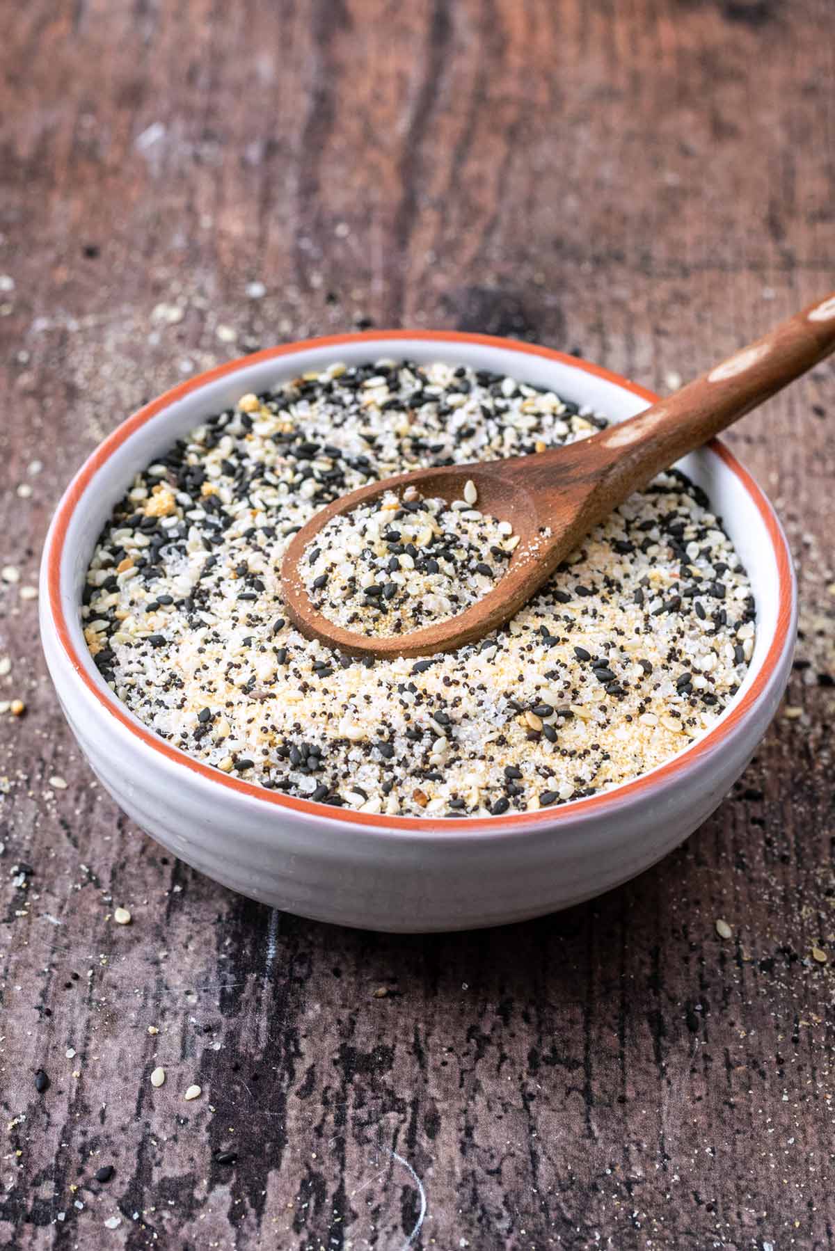 A spoon lifting some bagel seasoning from a small bowl.