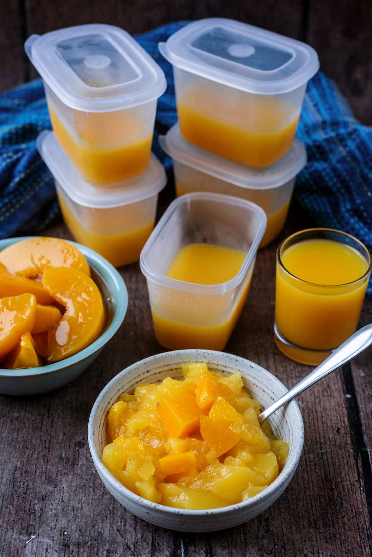 Plastic pots containing orange jelly with a bowl of jelly in front of them.