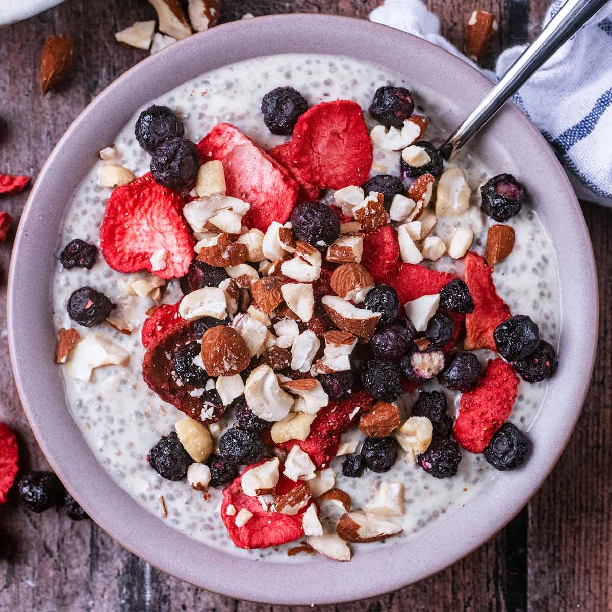 A bowl of Greek yogurt chia pudding topped with berries and crushed nuts.