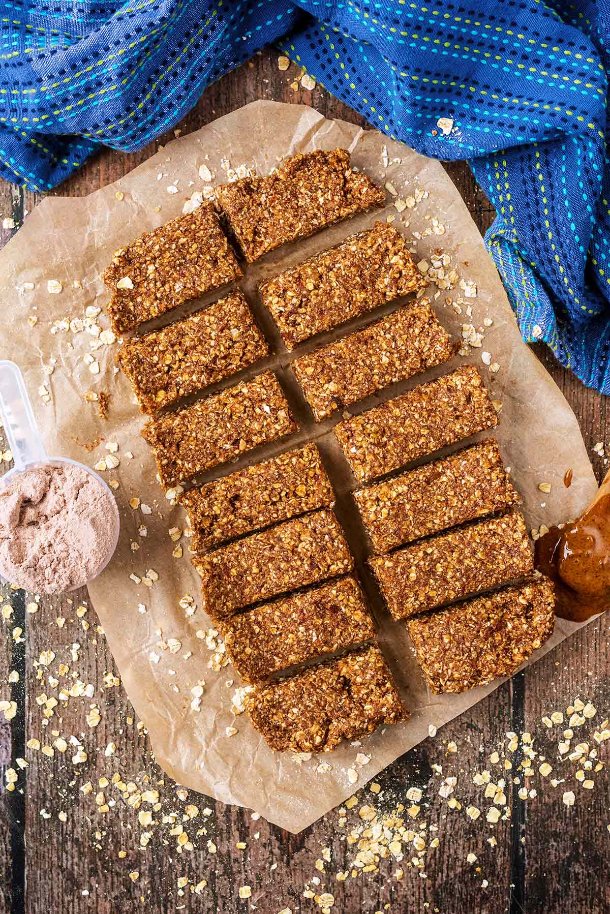 Protein bars on a sheet of parchment paper surrounded by scattered oats.