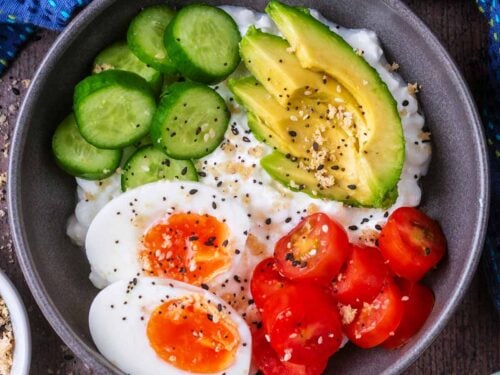 Cottage cheese bowl topped with boiled egg, sliced cucumber, avocado and tomato slices.