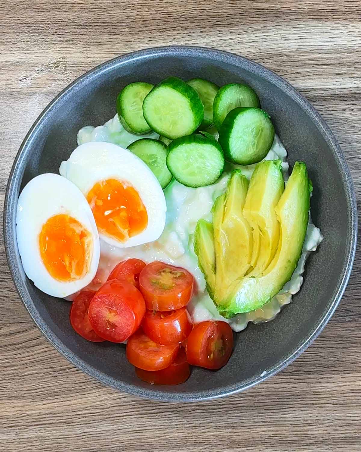 Boiled egg, cucumber, tomato and avocado added to the bowl.