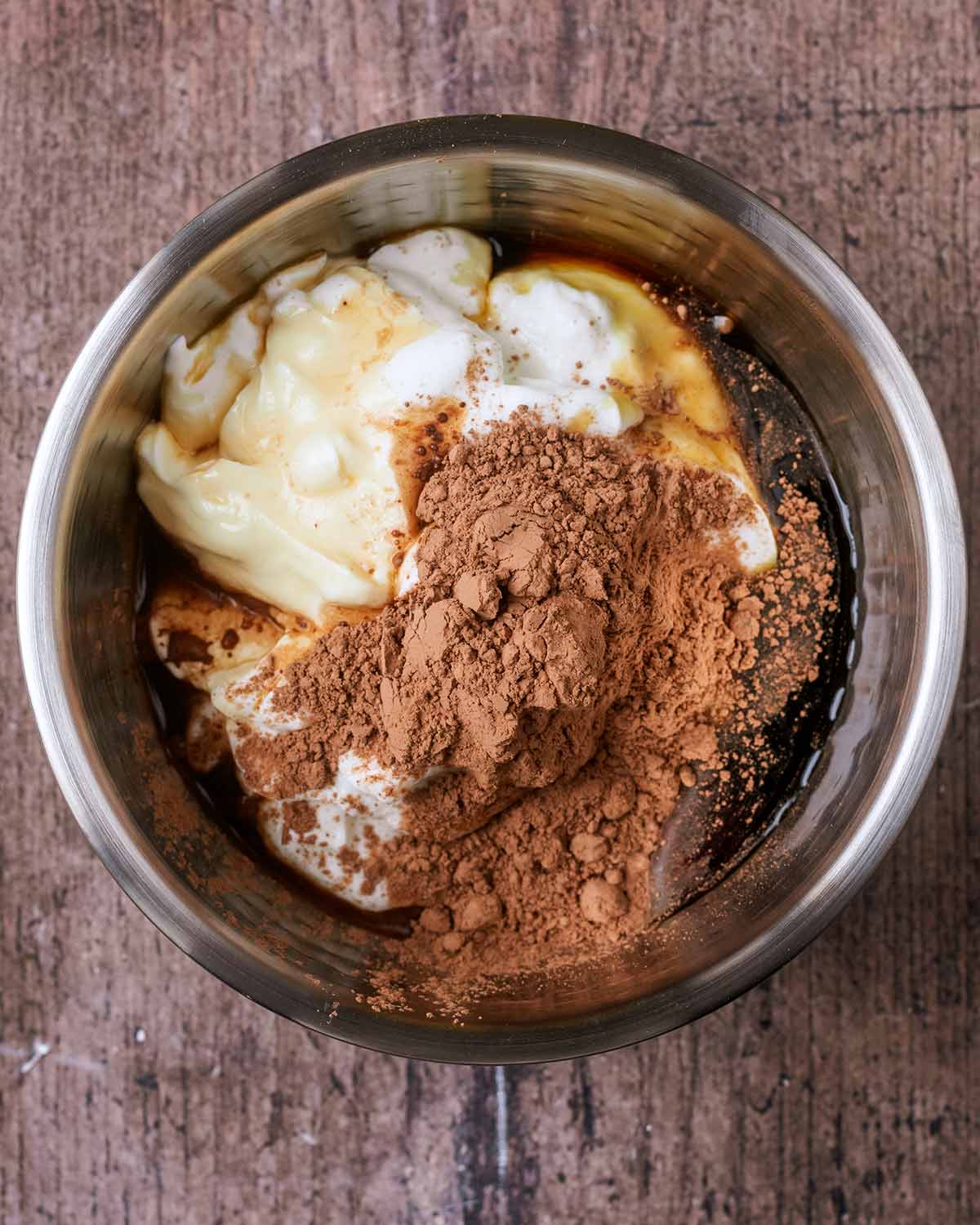 A mixing bowl containing yogurt, cacao powder, vanilla and maple syrup.