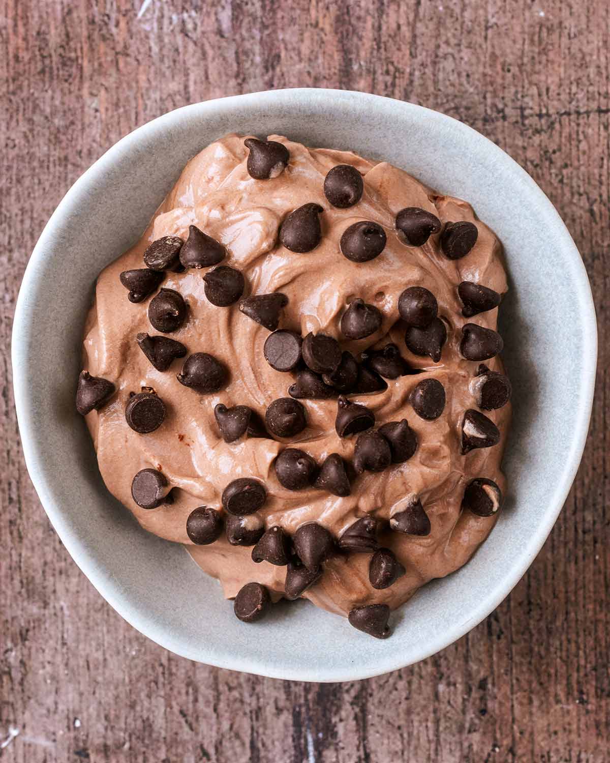 A serving bowl with chocolate yogurt topped with chocolate chips.