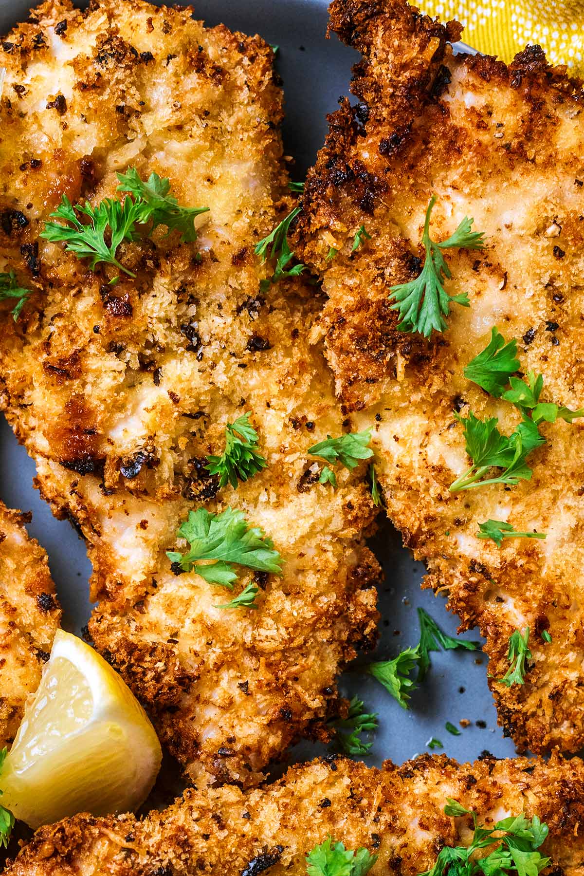 Breaded chicken cutlet topped with sprigs of parsley.