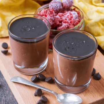 Two small glasses of cottage cheese chocolate mousse on a wooden board.