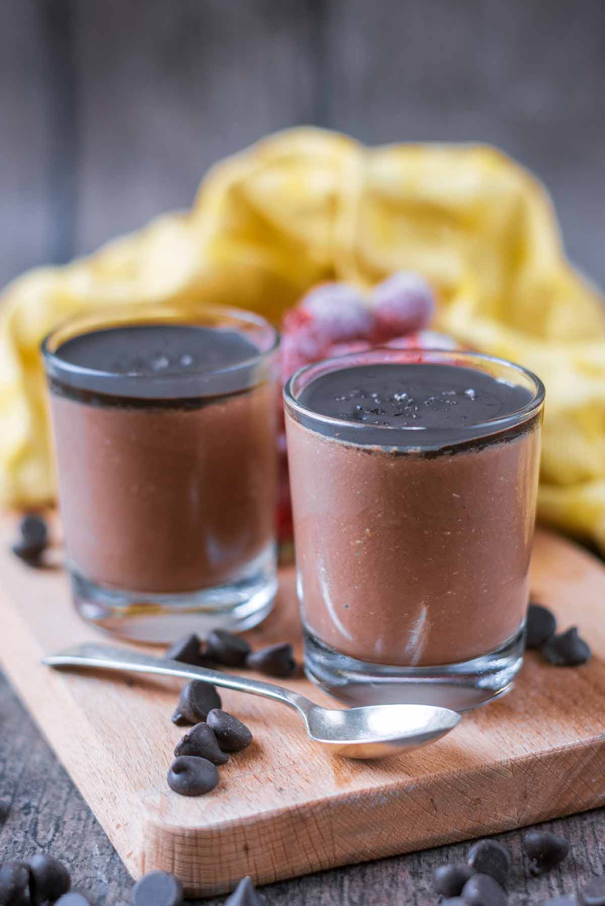 Two shot glasses filled with chocolate mouse and topped with dark chocolate.