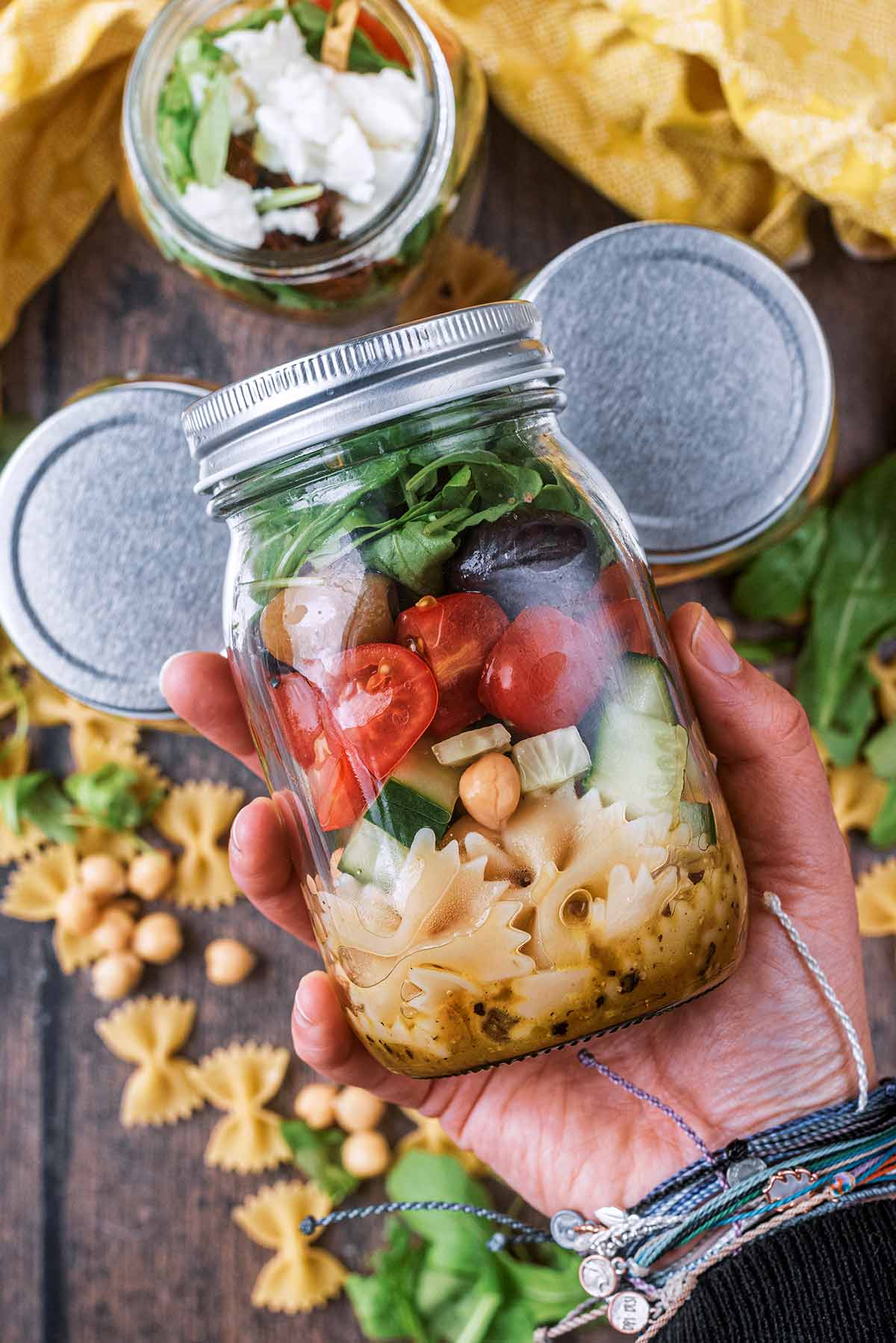 A hand holding a jar full of pasta salad.