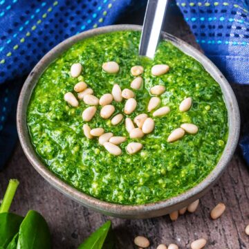 A bowl of spinach pesto topped with pine nuts.