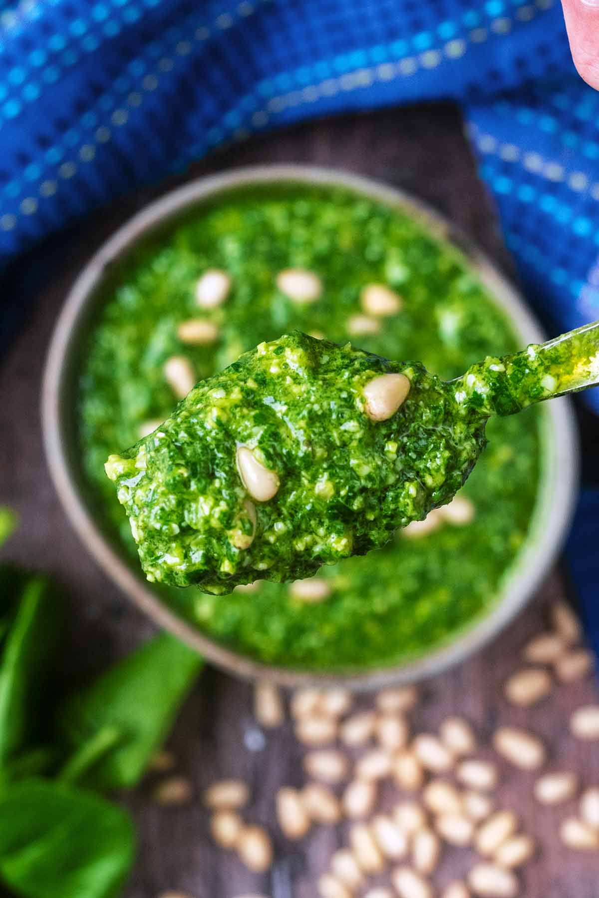 A spoon lifting some pesto out of a bowl.