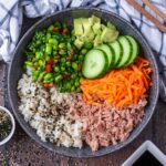 A tuna sushi bowl next to some soy sauce and furikake seasoning.