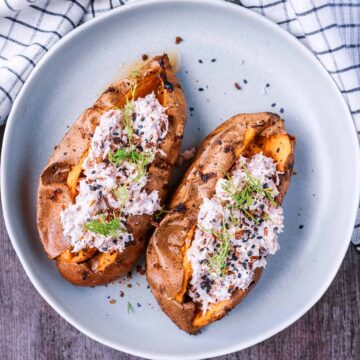 Two air fryer baked sweet potatoes on a plate toped with tuna mayo.