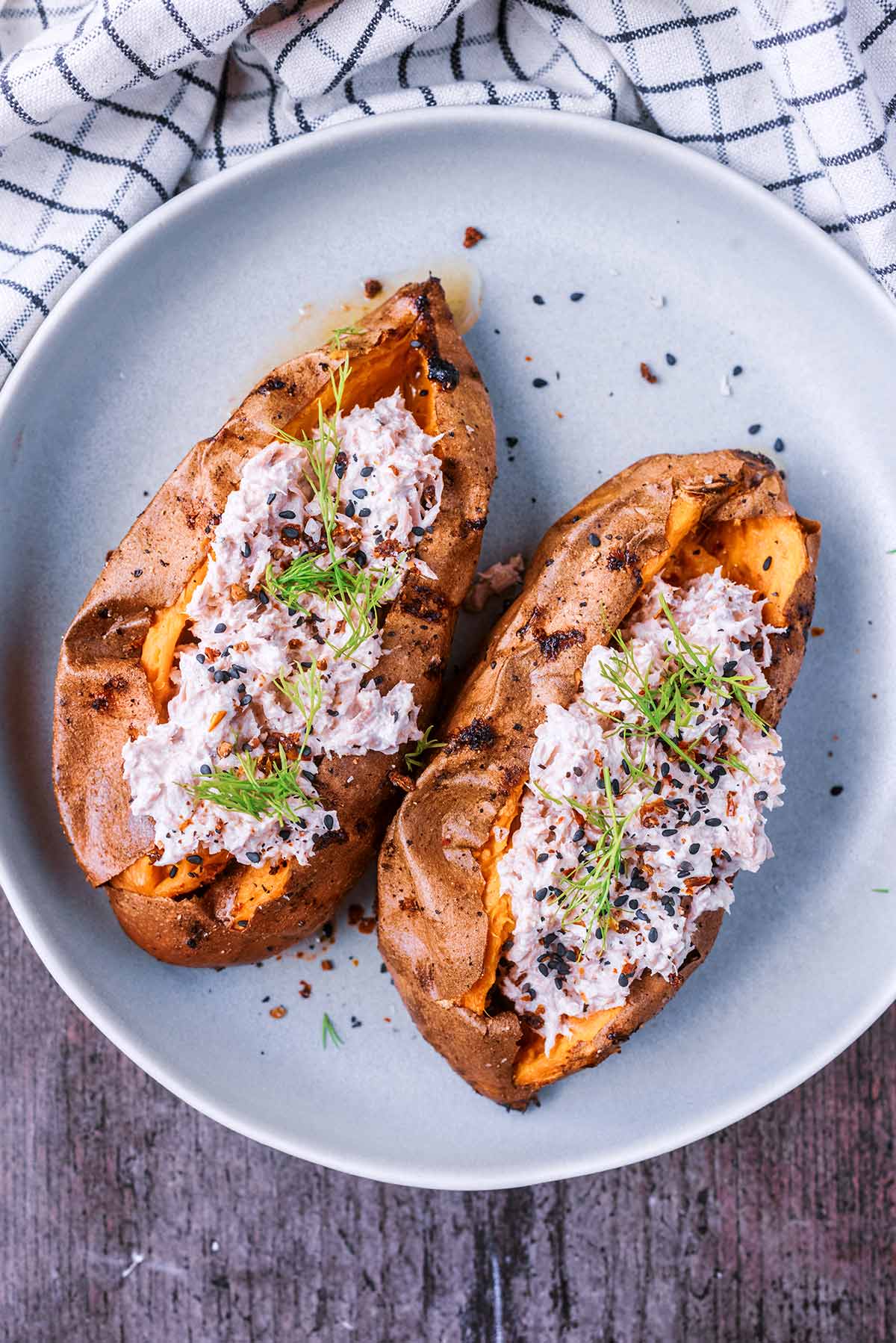 Baked sweet potatoes on a plate both with a tuna mayonnaise filling.