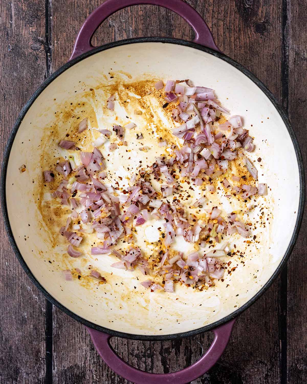 Chopped shallots and chilli flakes cooking in a pan.